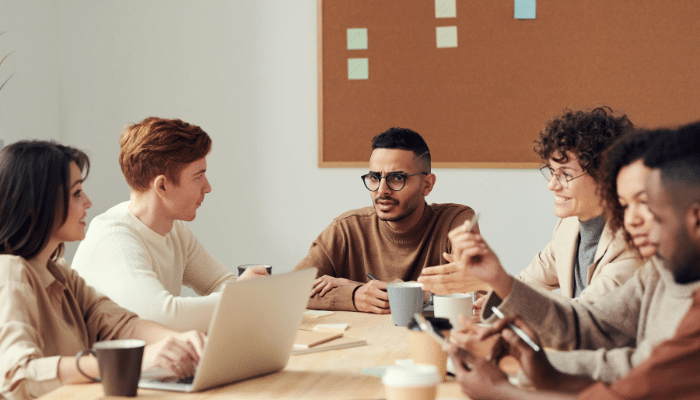 Team members collaborating and sharing ideas while seated around a table in a contemporary office environment.