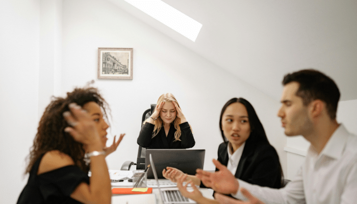 Cost of a Bad Hire: A frustrated team of professionals sitting together at a table in an office, focused on a discussion or brainstorming session.