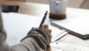 A woman's hand writing notes in a notebook, showcasing her focused engagement in the task.